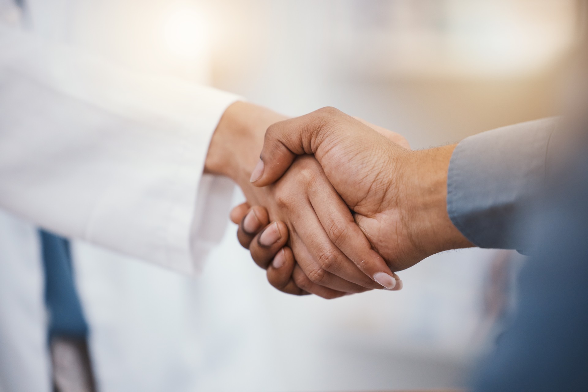 Doctor, patient and handshake in hospital thank you, welcome or greeting for medicine trust, help or medical consulting. Zoom, black man and shaking hands with pharmacy worker or healthcare employee